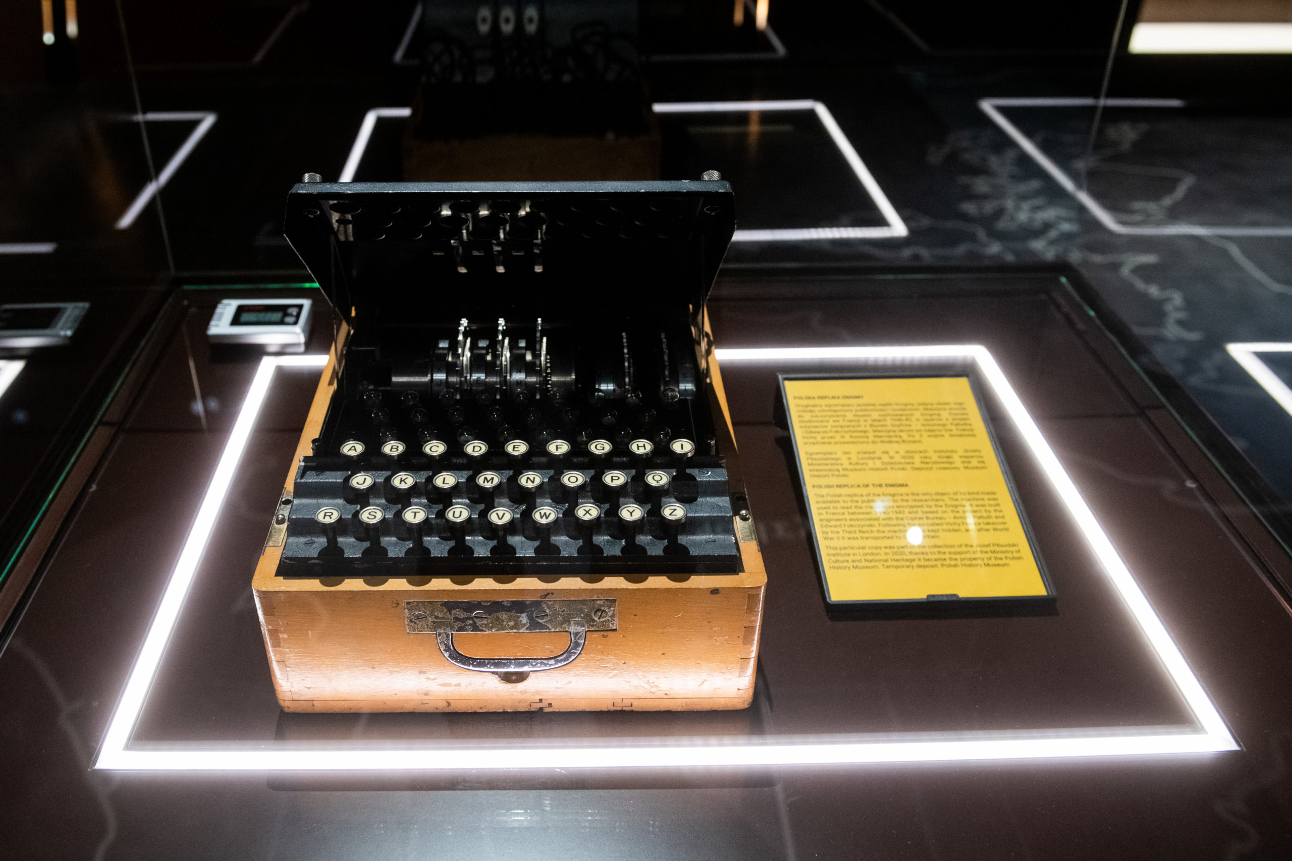 Enigma w gablocie, obok niej kartka informacyjna.